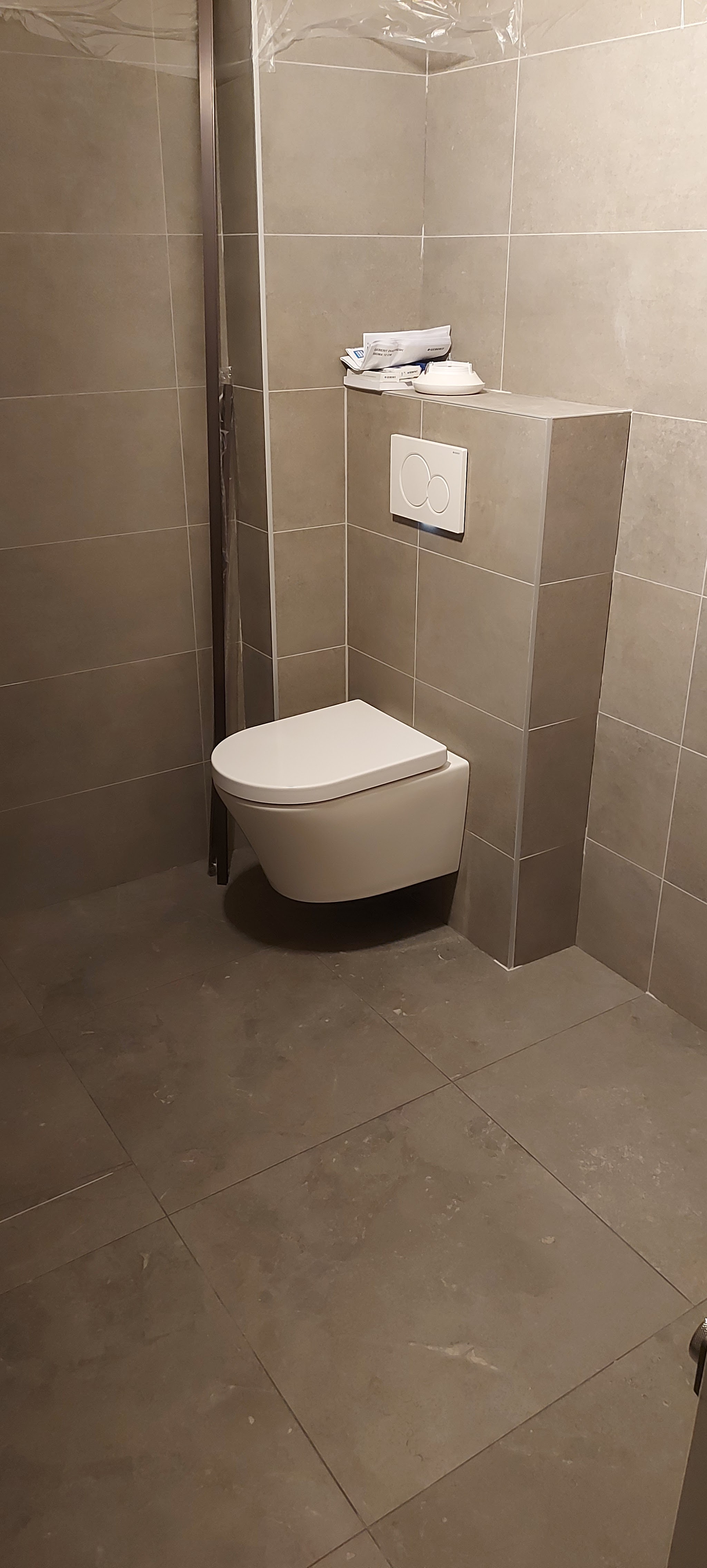 Afgewerkte wc-ruimte met een hangend toilet en grote grijze tegels